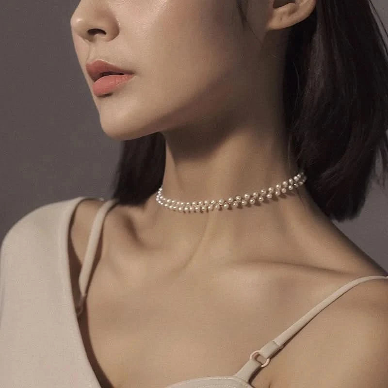 Close-up of a woman wearing a pearl choker necklace