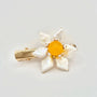 The image features a hair clip with a bright yellow center, surrounded by white baroque pearl petals. Each pearl petal is irregular in shape, adding a natural and organic feel to the design. The center of the flower is accented with small, sparkling stones that complement the gold-tone of the clip's hardware. The overall design resembles a sunny flower, set against a plain background to emphasize its vivid color and lustrous pearls.