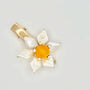 The image features a hair clip with a bright yellow center, surrounded by white baroque pearl petals. Each pearl petal is irregular in shape, adding a natural and organic feel to the design. The center of the flower is accented with small, sparkling stones that complement the gold-tone of the clip's hardware. The overall design resembles a sunny flower, set against a plain background to emphasize its vivid color and lustrous pearls.