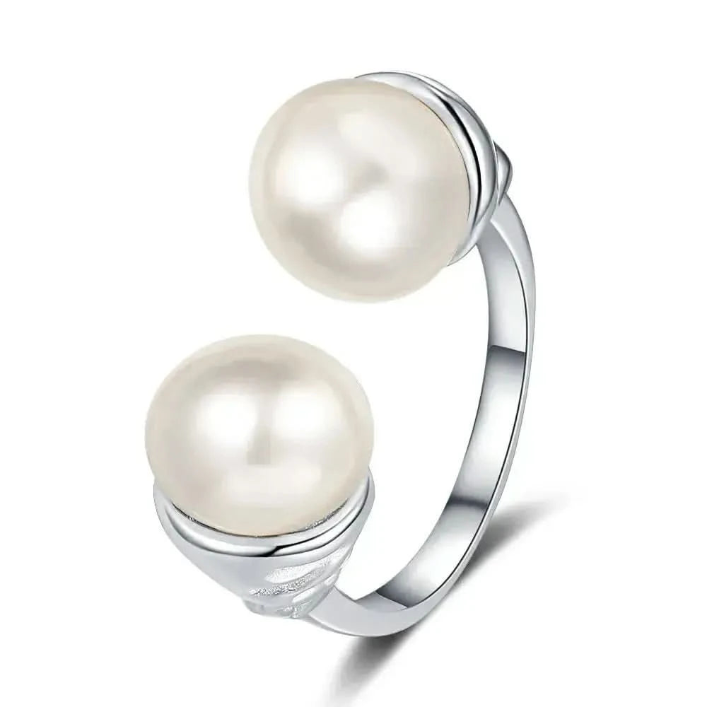 A unique sterling silver ring marked 'S925' indicating its purity, featuring a split-shank design that holds two large, lustrous pearls. The metal between the pearls is crafted to resemble a stylized floral or heart pattern, adding a decorative touch to the piece.