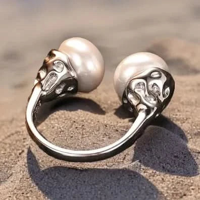 A unique sterling silver ring marked 'S925' indicating its purity, featuring a split-shank design that holds two large, lustrous pearls. The metal between the pearls is crafted to resemble a stylized floral or heart pattern, adding a decorative touch to the piece.