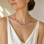 Carved rhodochrosite flower and white stone beaded necklace worn at a three quarter angle