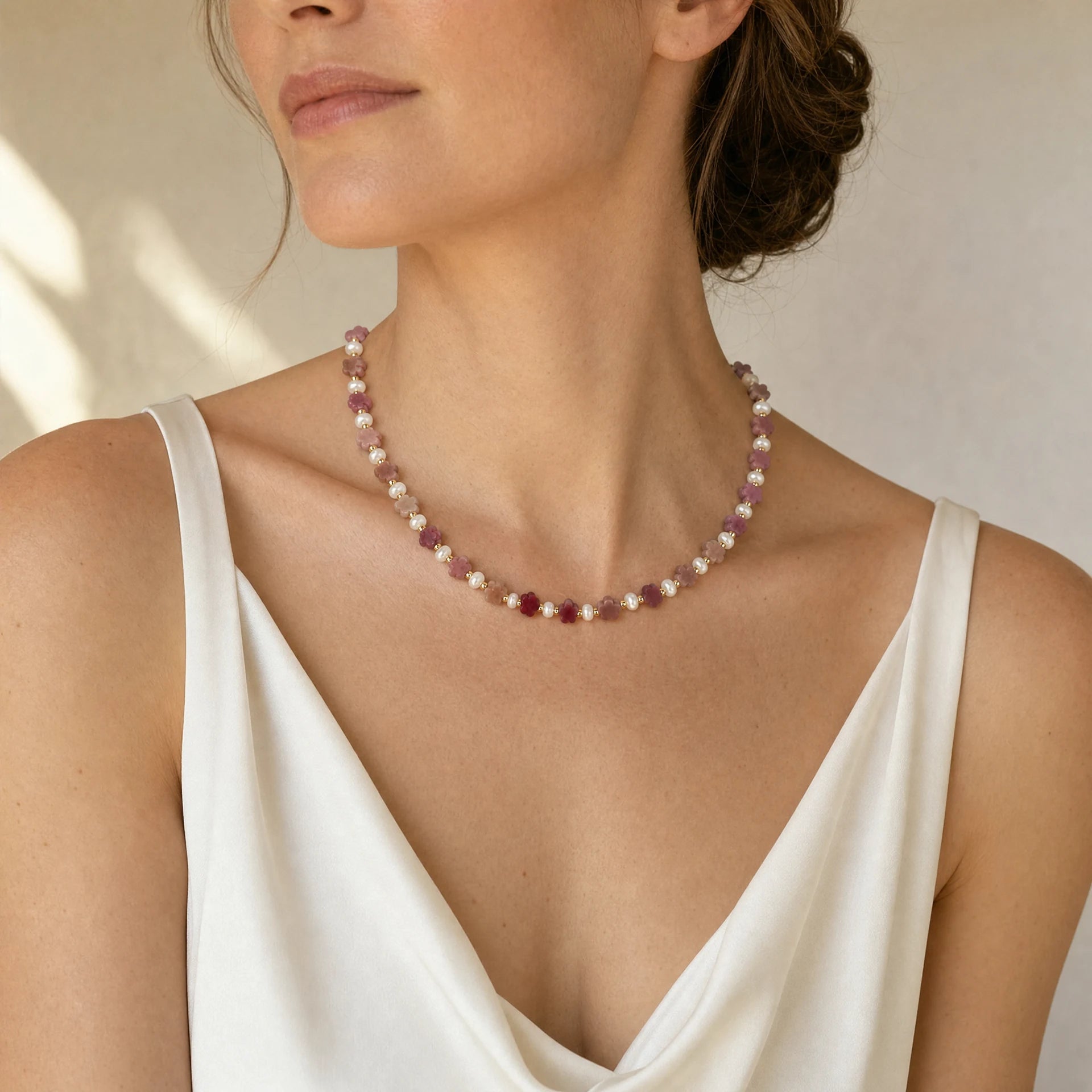 Carved rhodochrosite flower and white stone beaded necklace worn at a three quarter angle