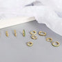 Gold hoop earrings with green gemstones on a gray surface