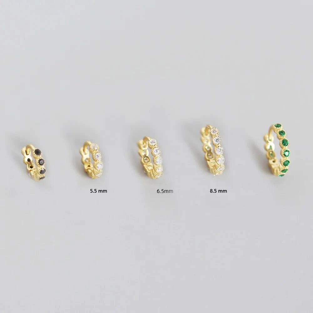 Set of gold hoop earrings with varying sizes on a gray background