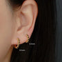 Gold hoop earrings with black stones worn by a person, showing ear and hair details.