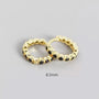 Pair of gold hoop earrings with black stones on a gray background