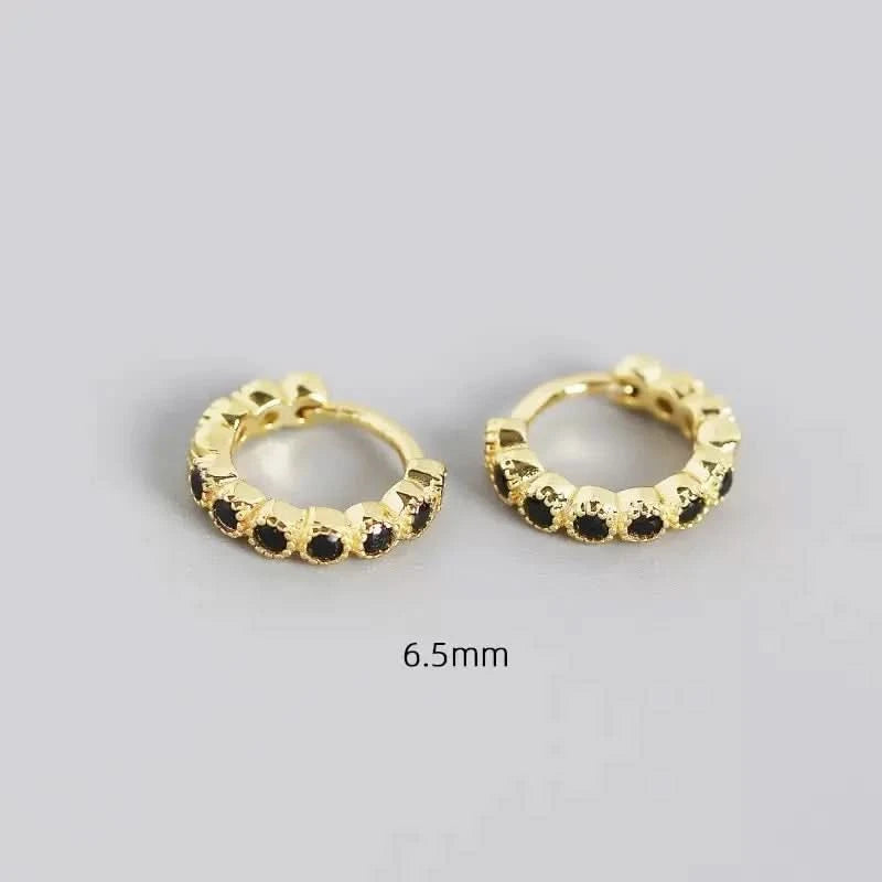Gold hoop earrings with black stones on a gray background