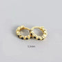 Gold hoop earrings with black stones on a gray background