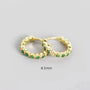Gold hoop earrings with green gemstones on a gray background