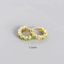 Gold hoop earrings with green gemstones on a gray background