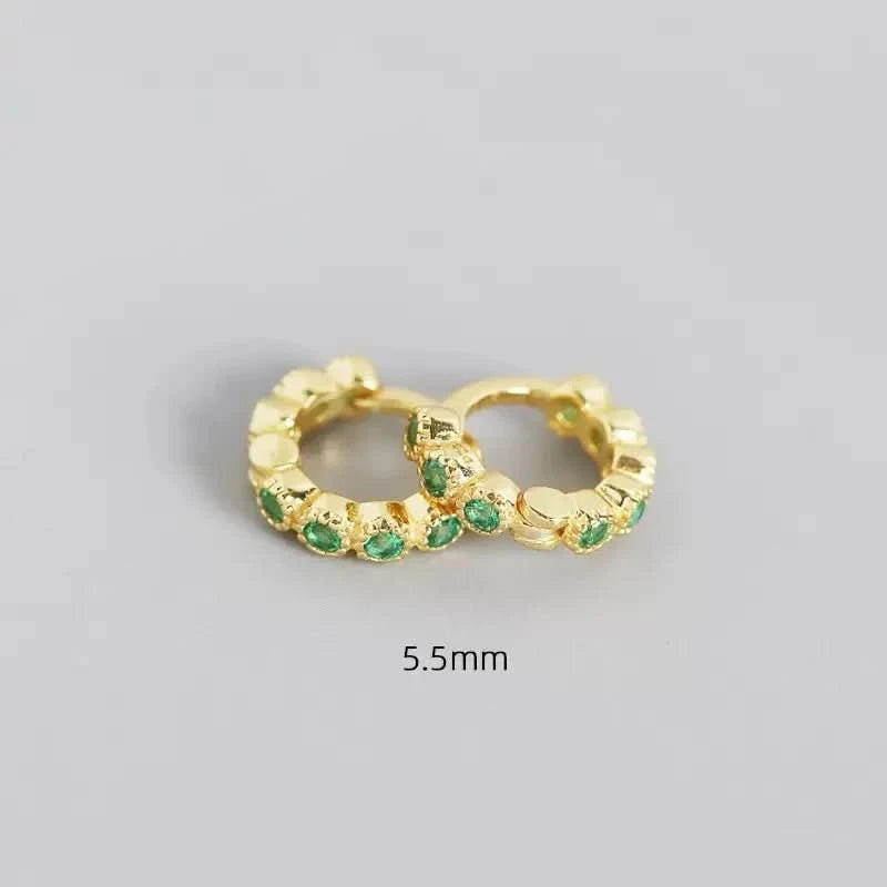 Gold hoop earrings with green gemstones on a gray background