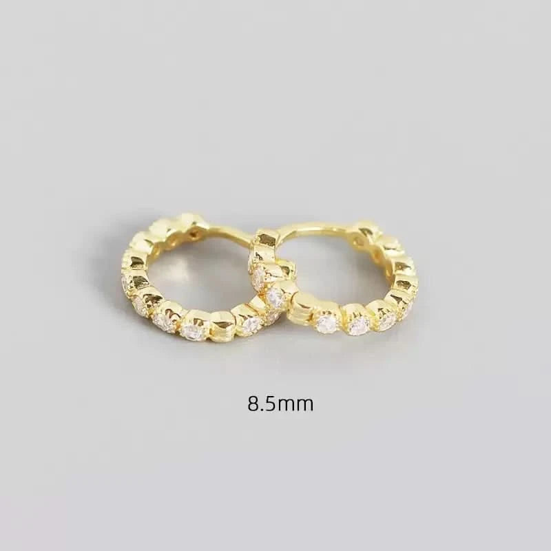 Gold hoop earrings with embedded stones on a gray background