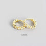 Gold hoop earrings with embedded stones on a gray background