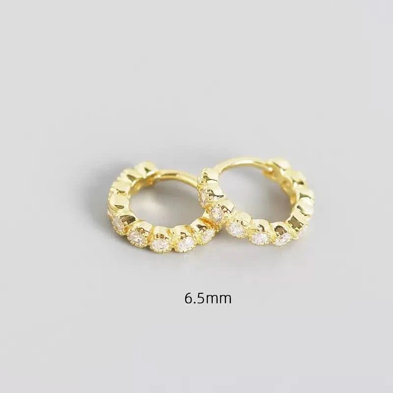 Gold hoop earrings with embedded stones on a gray background