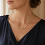 Model wearing gold-tone angel wing pearl necklace with white pearl centrepiece