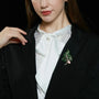 Green crystal botanical branch brooch worn on a black blazer with a white blouse
