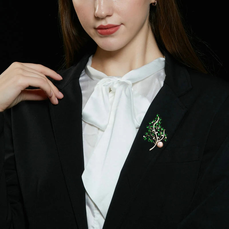 Green crystal botanical branch brooch worn on a black blazer with a white blouse