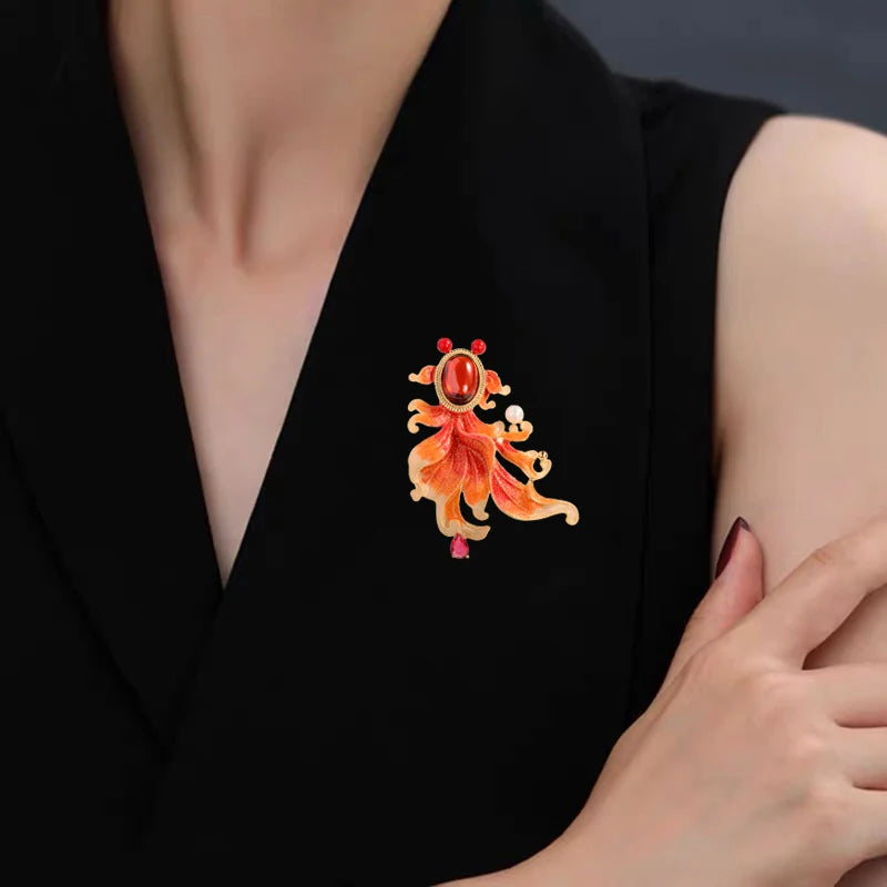 Goldfish brooch with amber-orange crystal body worn as a statement accessory on a black blazer