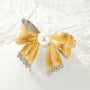 Detail of gold and silver ribbon folds, freshwater pearl and cubic zirconia scalloped ends on a light background