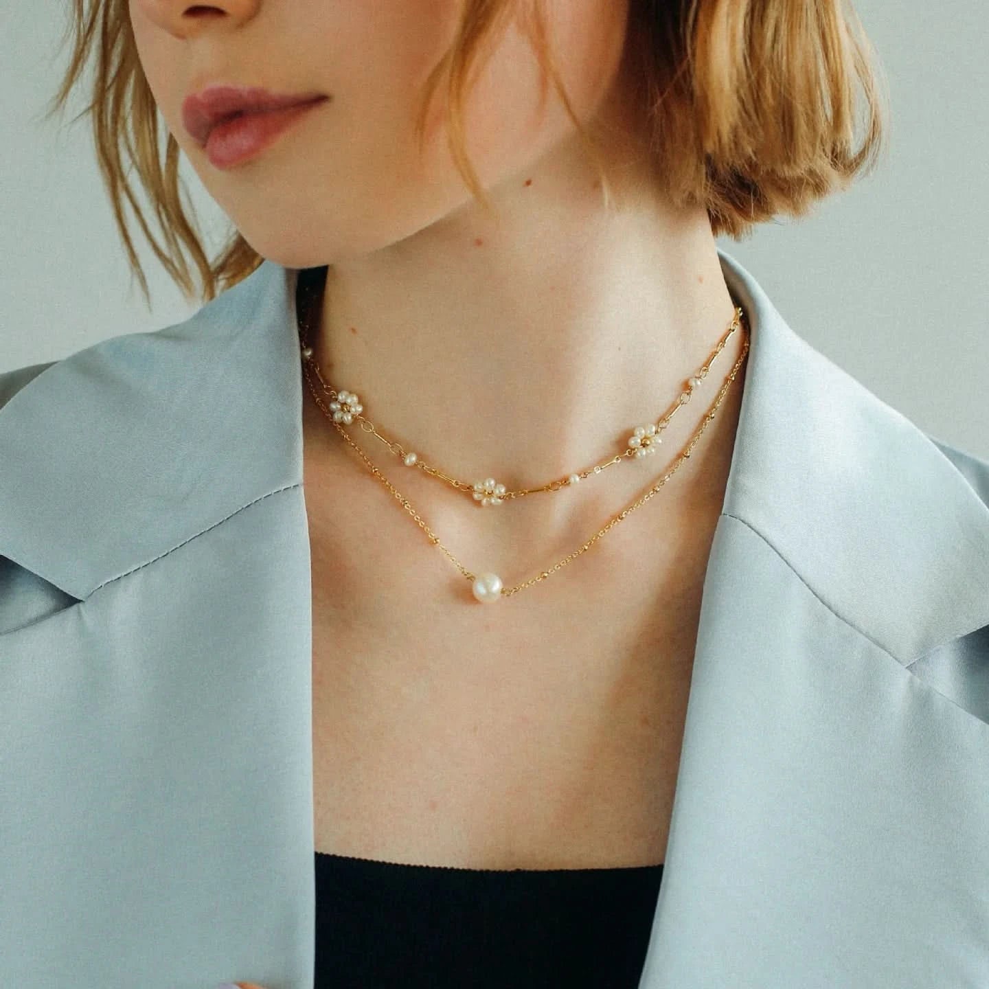 Close-up of a person wearing a delicate gold necklace with pearls 