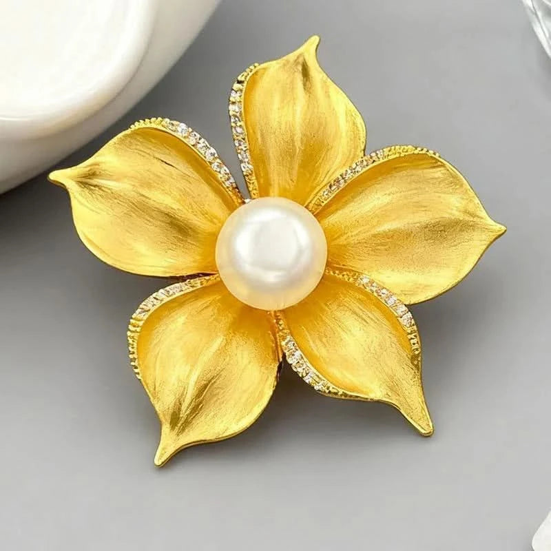 Gold flower pearl brooch detail showing sculpted petals and cubic zirconia edging
