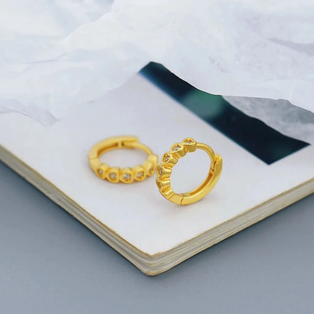 Gold hoop earrings on a white surface with a blurred background