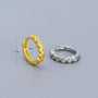 Gold and silver hoop earrings on a light gray background