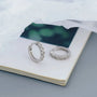 Two silver rings on a white surface with a blurred green background