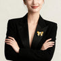 Two-tone gold and silver bow brooch with freshwater pearl worn on a black blazer