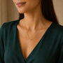 Model wearing minimalist gold-tone necklace with a smooth horizontal fish centrepiece