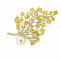 Yellow crystal branch brooch with clear crystals, pearl accent and gold-tone setting on a white background