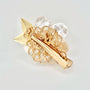 Gold hair clip with a pearl flower design, green jade center, and sparkling accents on a light background.