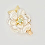 Gold hair clip with a pearl flower design, green jade center, and sparkling accents on a light background.