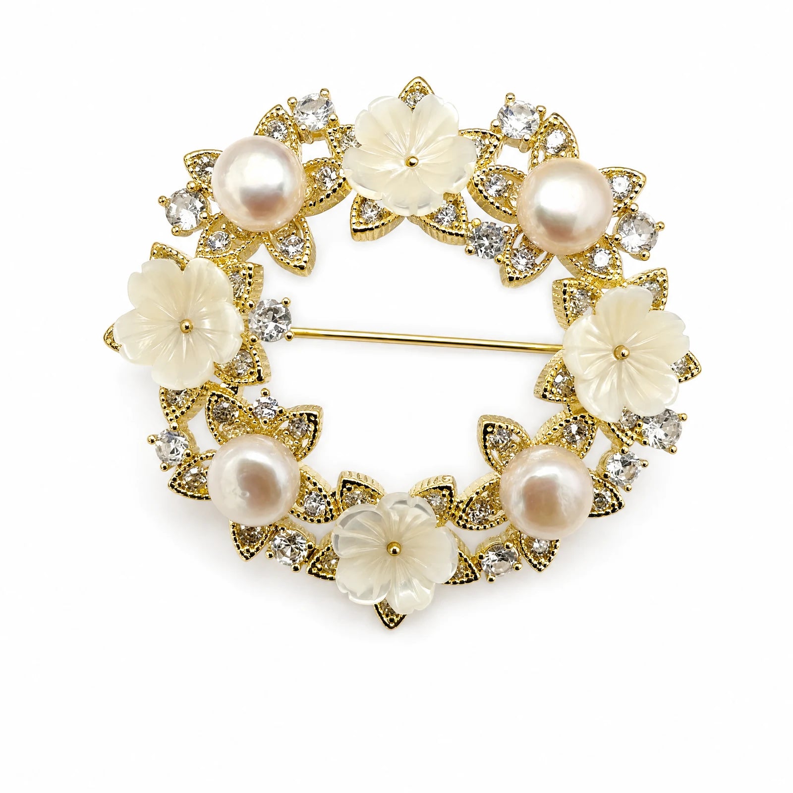 White flower and pearl wreath brooch with clear crystals and gold-tone leaves on a white background