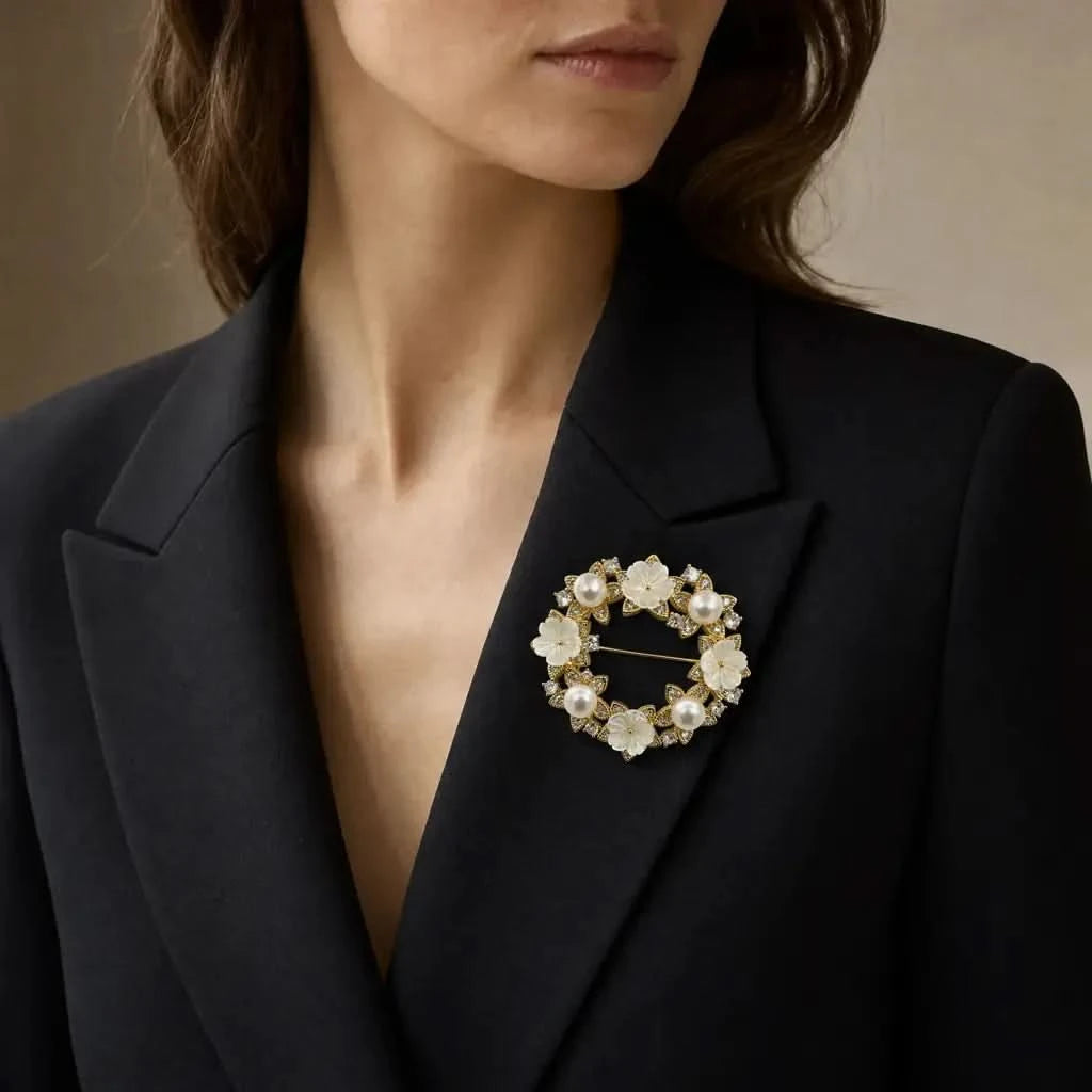 White flower and pearl wreath brooch worn on a black blazer for wedding or occasion styling