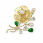 Mother-of-pearl floral bouquet brooch with pearl, green stone and cubic zirconia accents on a white background