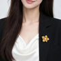 Freshwater pearl gold flower brooch worn on a black blazer lapel