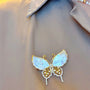 Butterfly-shaped brooch with gold and white design on a fabric background