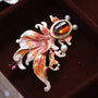 Goldfish brooch with red-orange enamel fins, crystal accents and pearl-effect detail on a velvet background