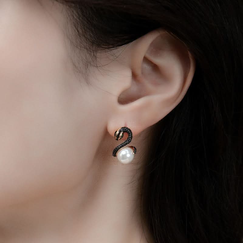 A close-up view of a woman's profile showcasing a unique earring. The earring features a black serpentine design with delicate crystal embellishments, leading down to a classic white pearl. The design gives a contemporary twist to the timeless pearl earring, blending modernity with elegance.