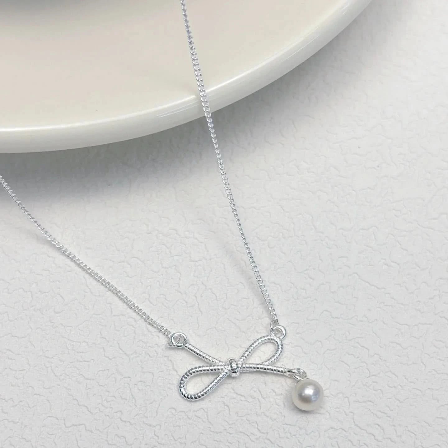 Silver necklace with a bow and pearl pendant 