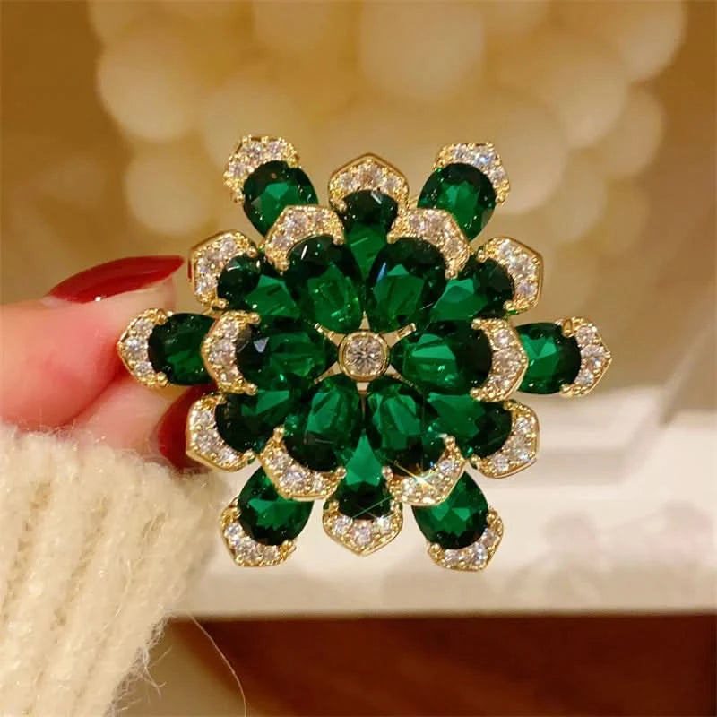 Close-up of faceted green pear-shaped crystals and clear crystal petal edges on an emerald-green flower brooch