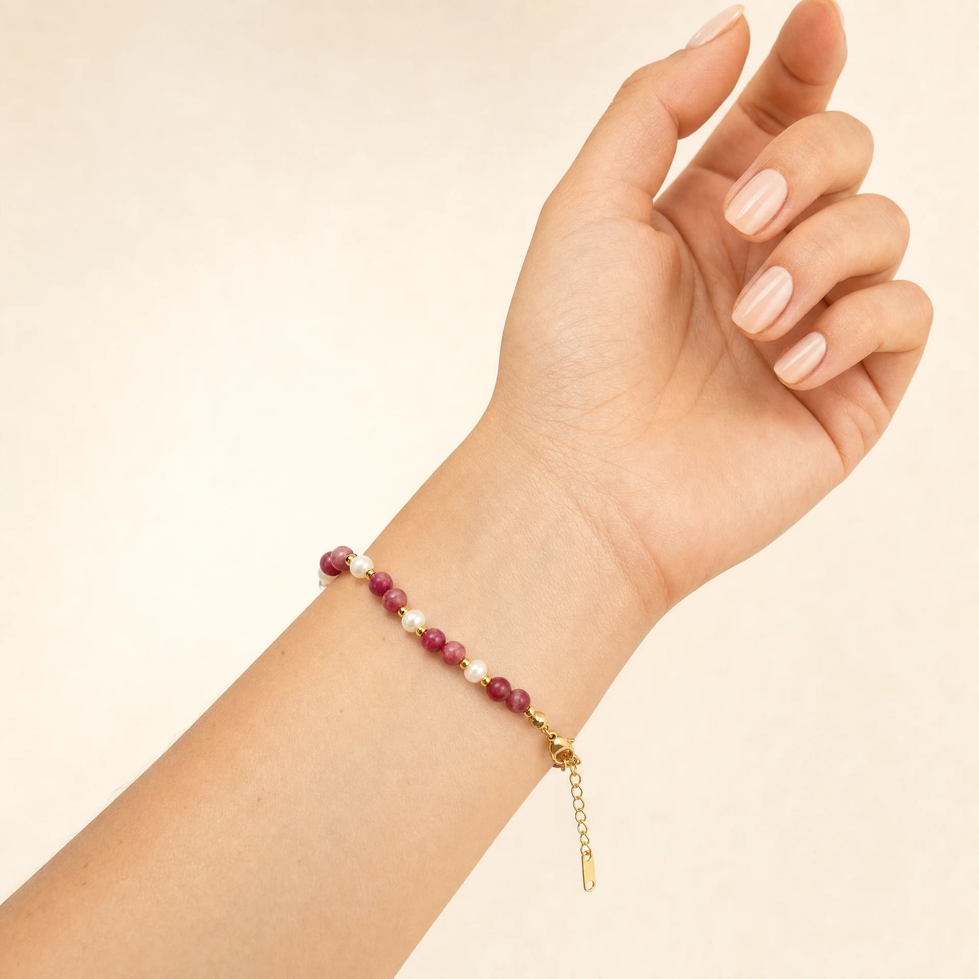 Rhodonite and mother-of-pearl beaded bracelet with gold-tone spacers worn on the wrist