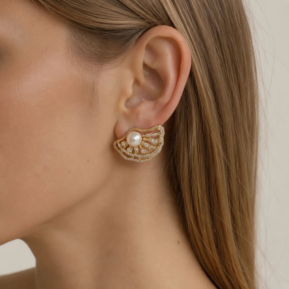 Model wearing gold-tone freshwater pearl ginkgo leaf stud earrings with clear zircon details
