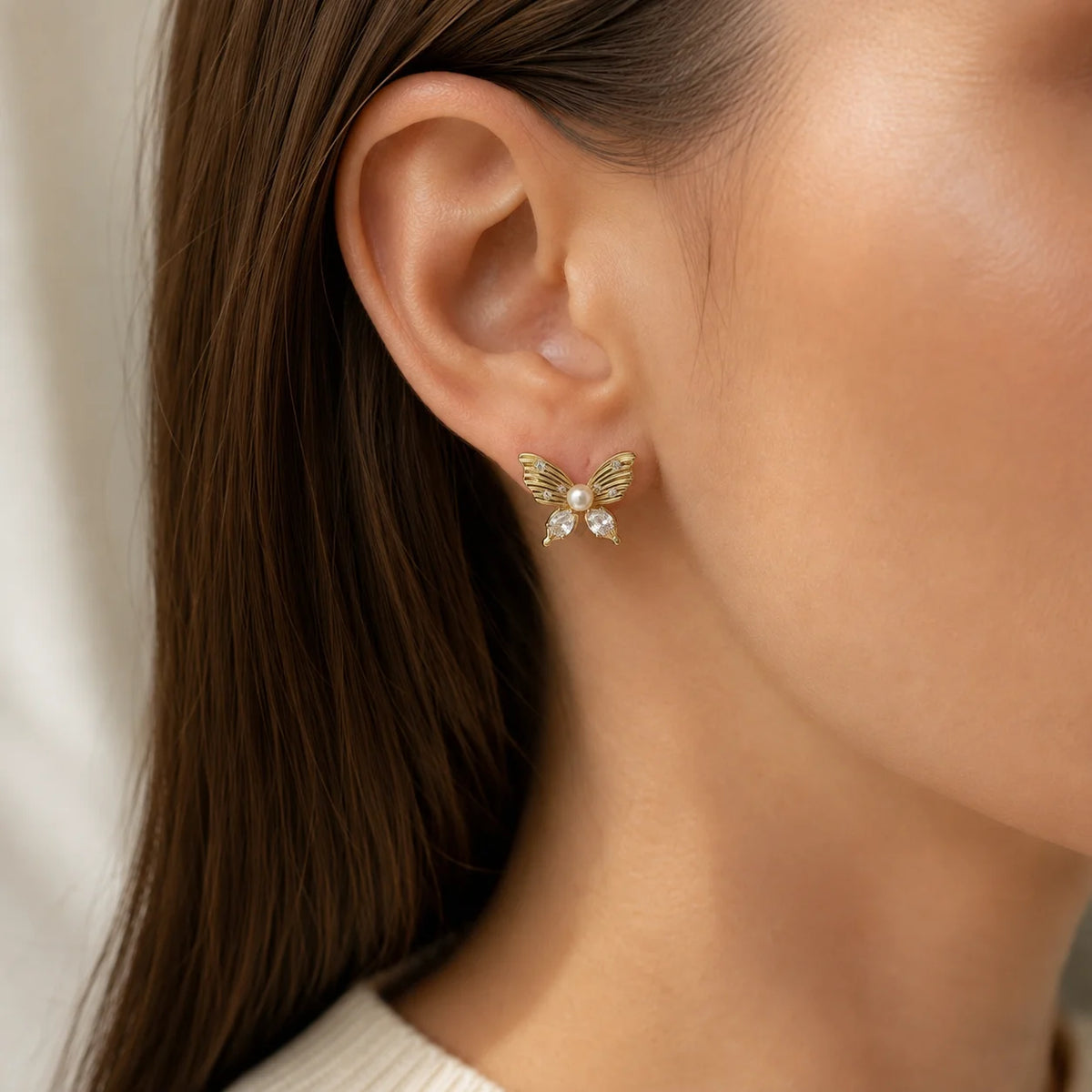 Model wearing gold-tone freshwater pearl butterfly stud earrings with clear crystal accents