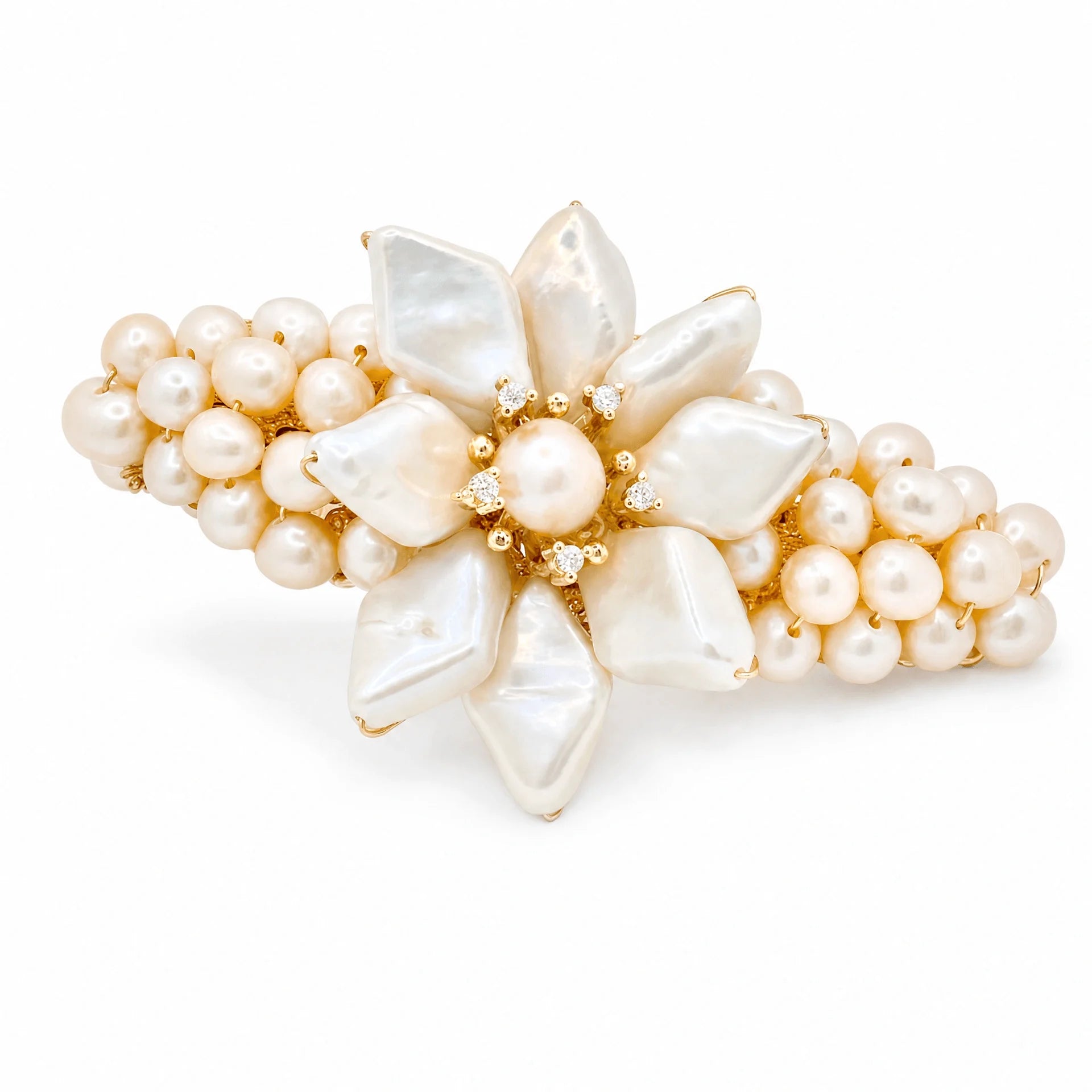 A gold-tone hair claw clip decorated with a central flower motif made of irregular white baroque pearls and surrounded by clusters of small round pearls, accented with tiny clear crystals.