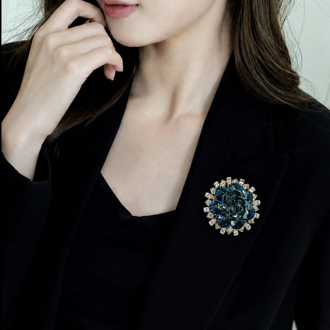 Teal crystal layered flower brooch worn on a black blazer