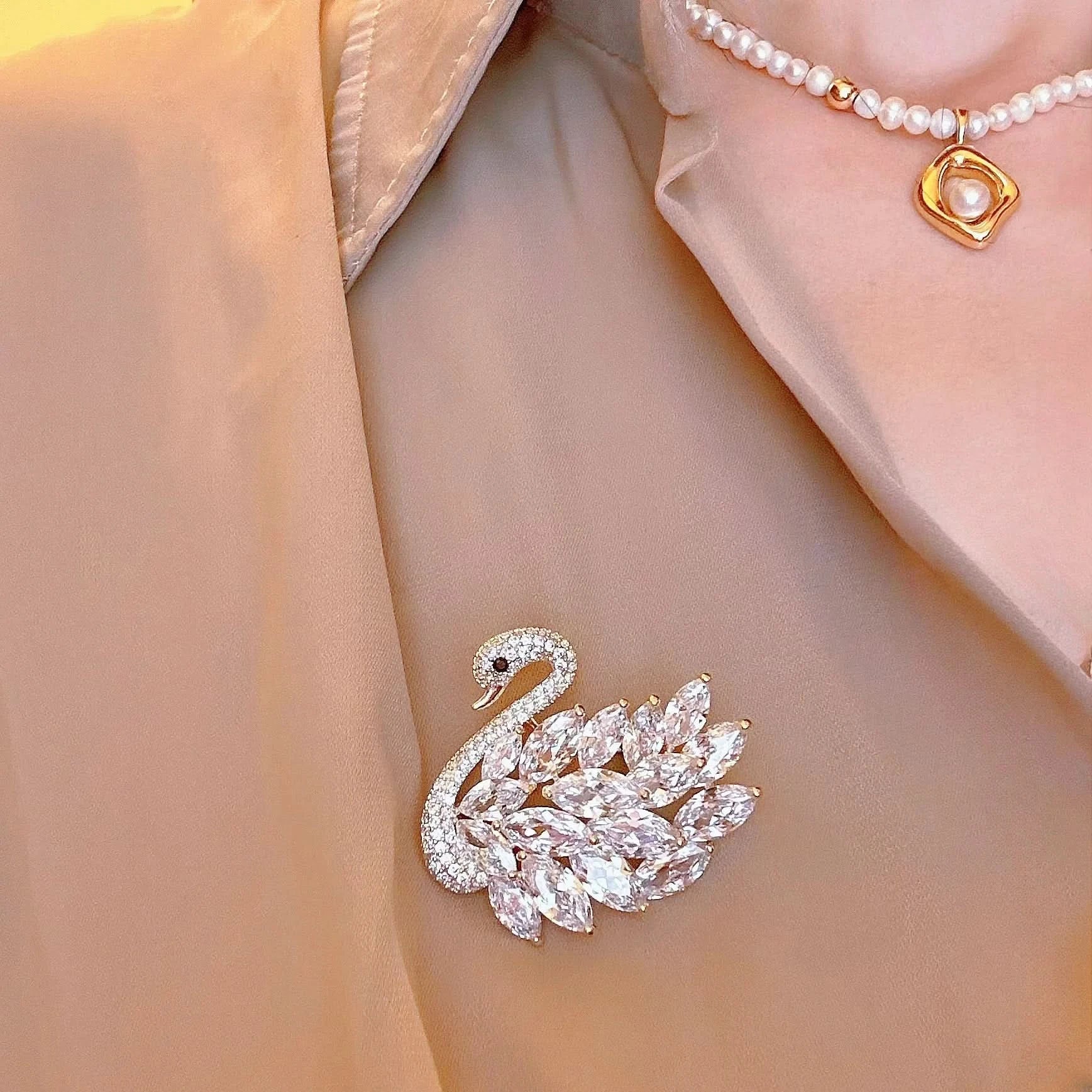 Gold swan brooch on a beige fabric background
