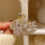 Gold and crystal swan brooch held by a hand against a neutral background